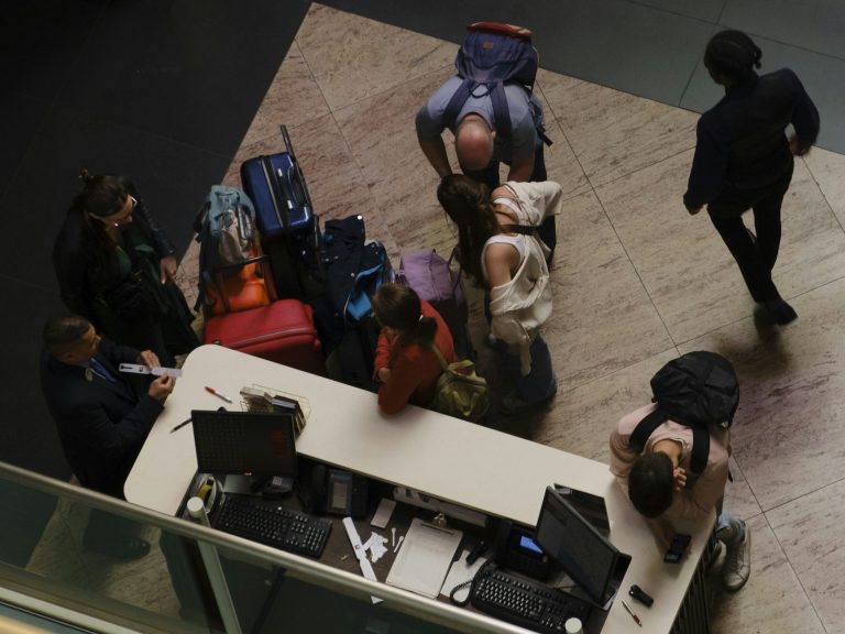 groupe de personnes autour d'un comptoir d'enregistrement avec des valises et des bagages.